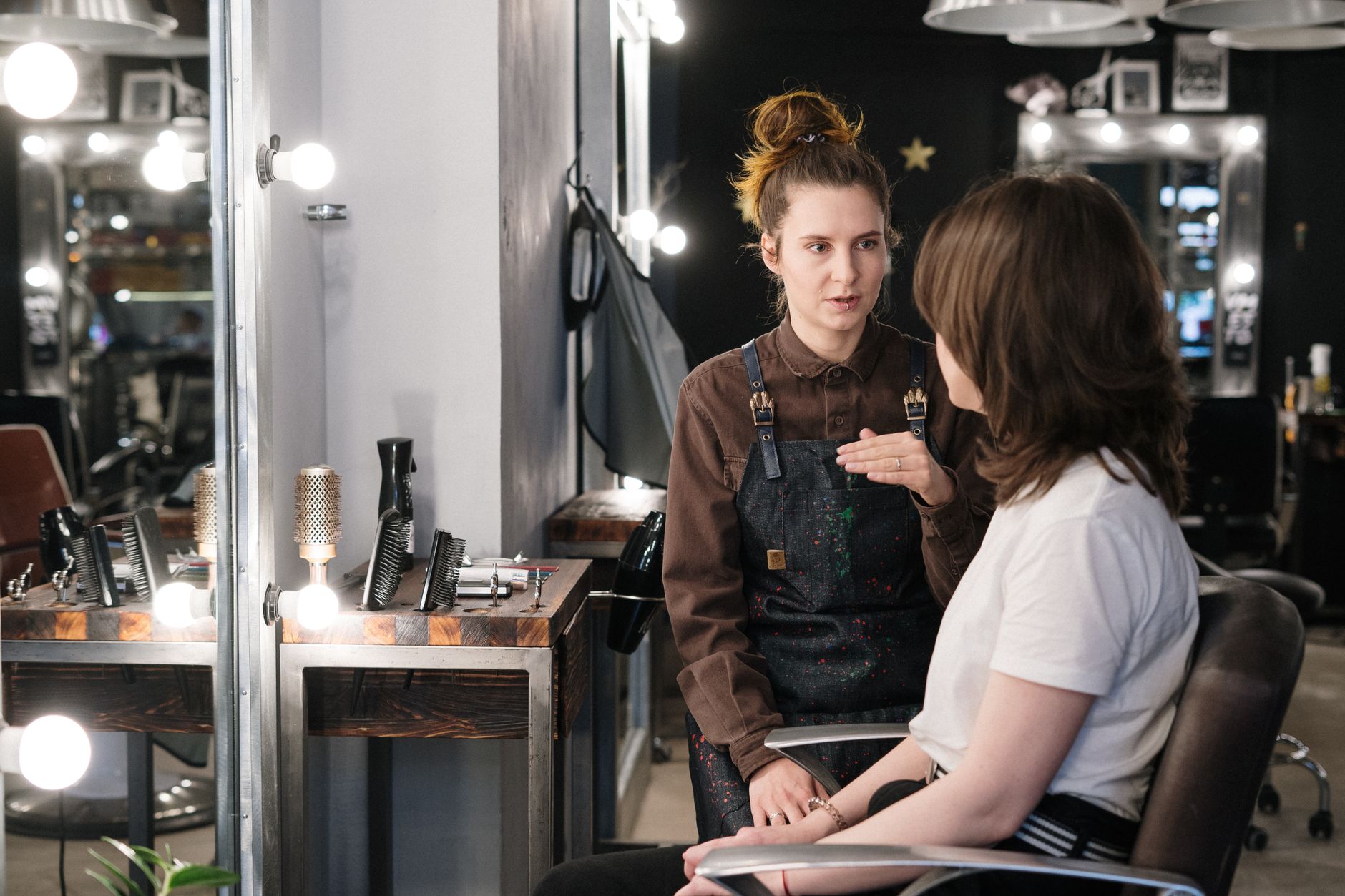 Hairstylist consults with client seated in salon chair during hair analysis appointment