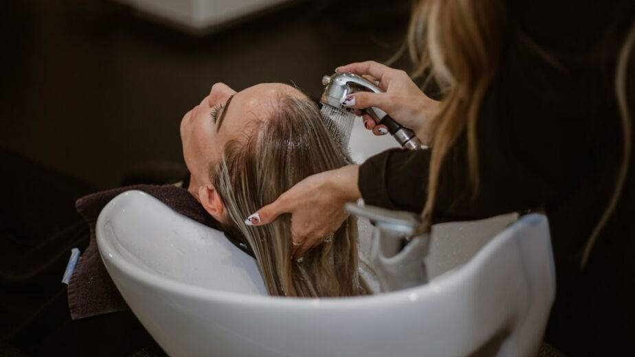 Frau wird beim Haarbotox-Treatment am Waschbecken im Salon behandelt