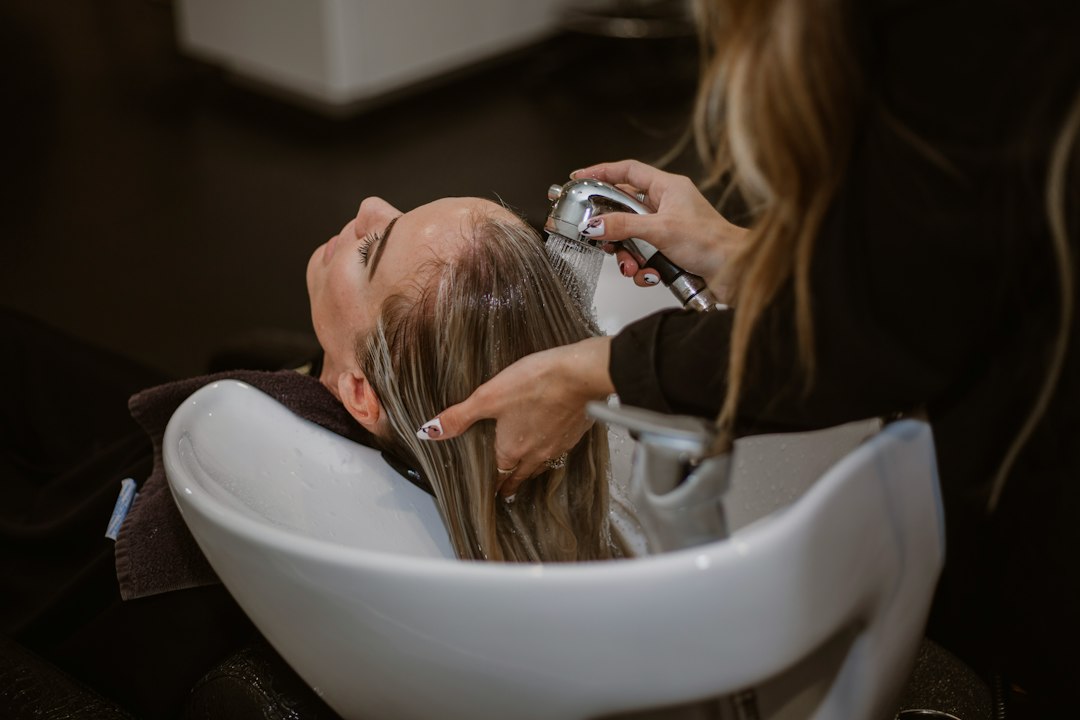 Frau wird beim Haarbotox-Treatment am Waschbecken im Salon behandelt