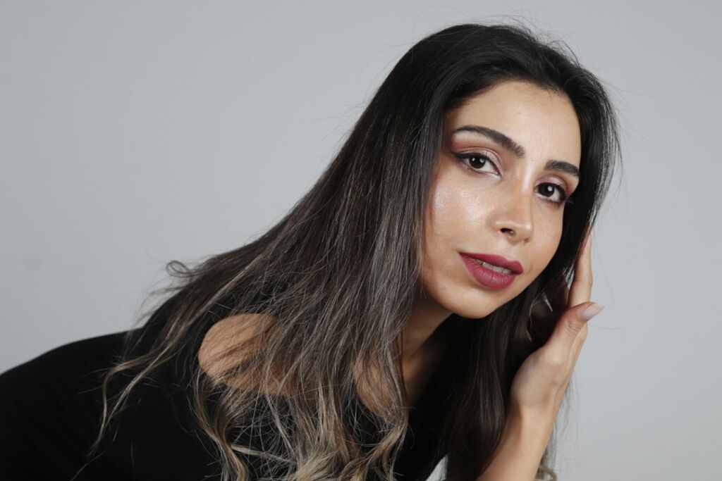 Frau mit sehr dunklem Haar und subtilen aufgehellten Spitzen als Beispiel für Balayage-Nuancen