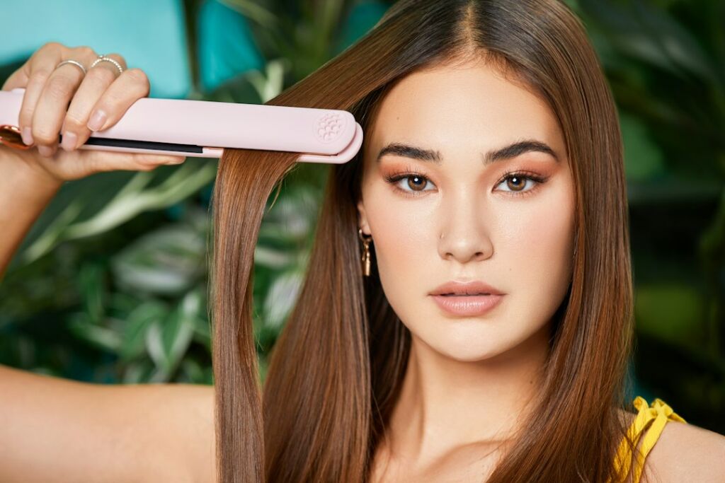 Frau glättet ihr Haar mit einem Glätteisen – die Keratin-Behandlung arbeitet mit Hitze, um die Haarfaser zu versiegeln